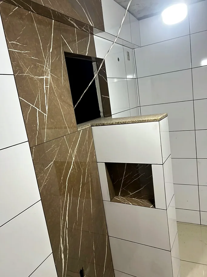 Banheiro com porcelanato marrom marmorizado e branco, bancada com nicho