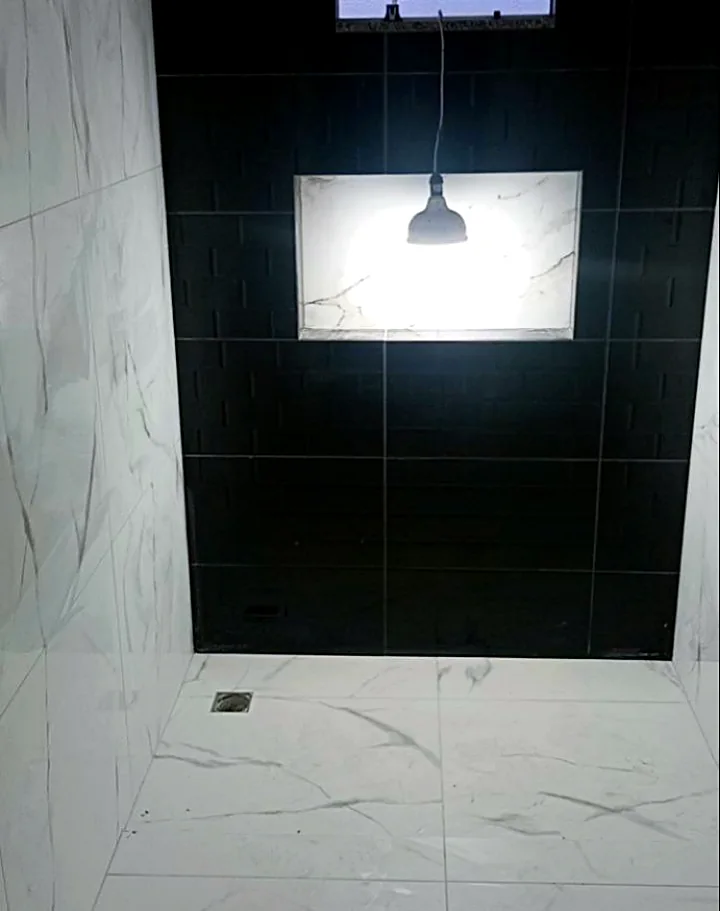 Box com parede preta e nicho iluminado em porcelanato marmorizado