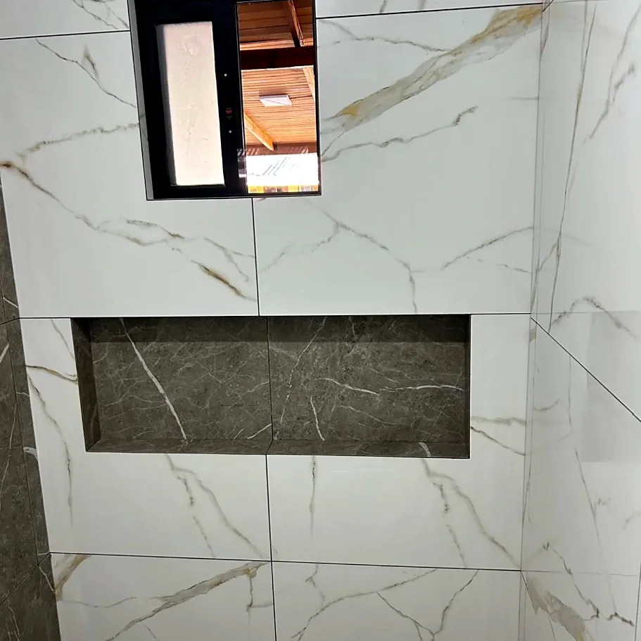Nicho embutido em porcelanato escuro dentro de parede de porcelanato branco com veios dourados